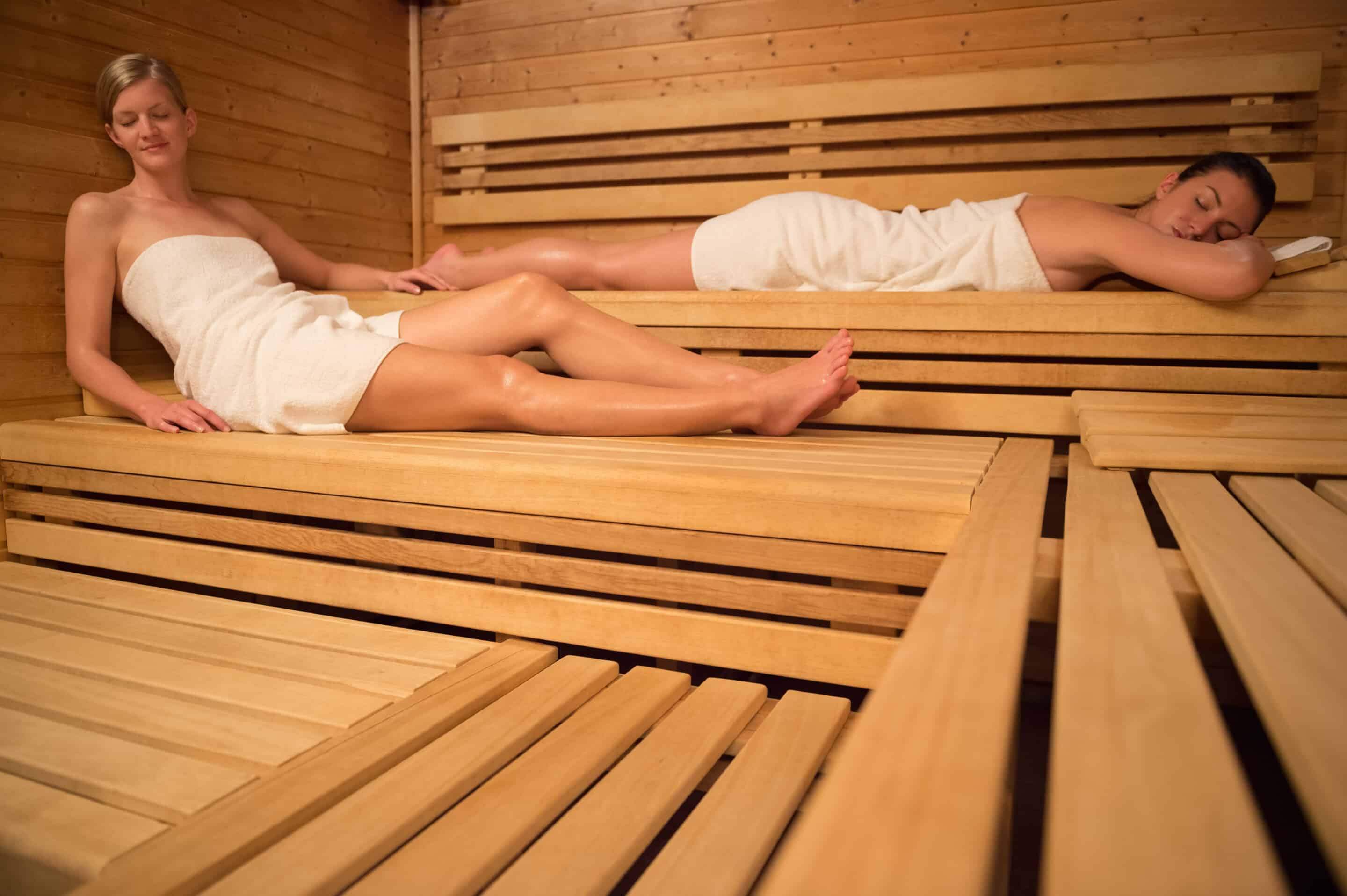 Two women relaxing on wooden benches in sauna. Trying a Nordic Spa in Québec City offers the chance to experience a choice of thermotherapies.
