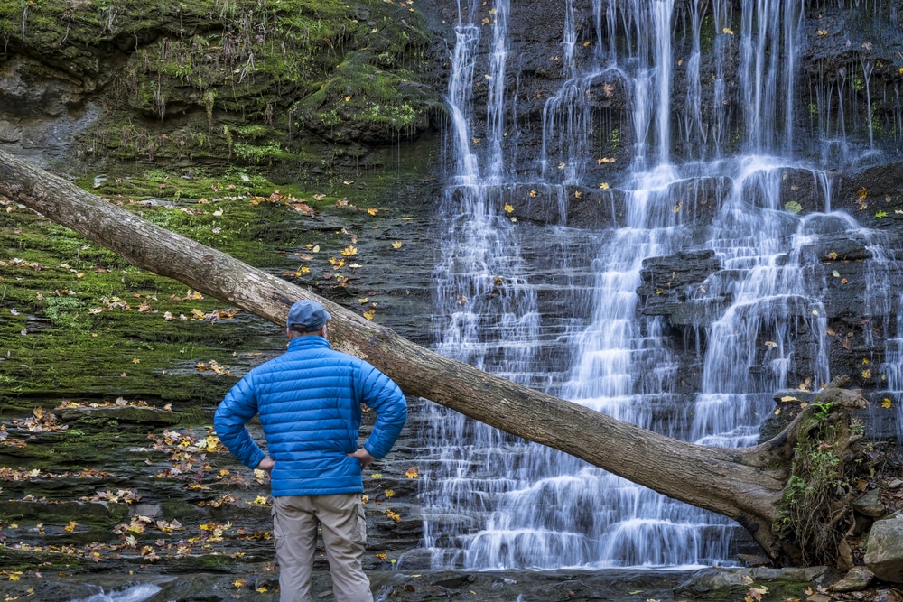 Jackson Falls at Natchez Trace Parkway with a man standing in front looking at the waterfall. A romantic getaway for couples