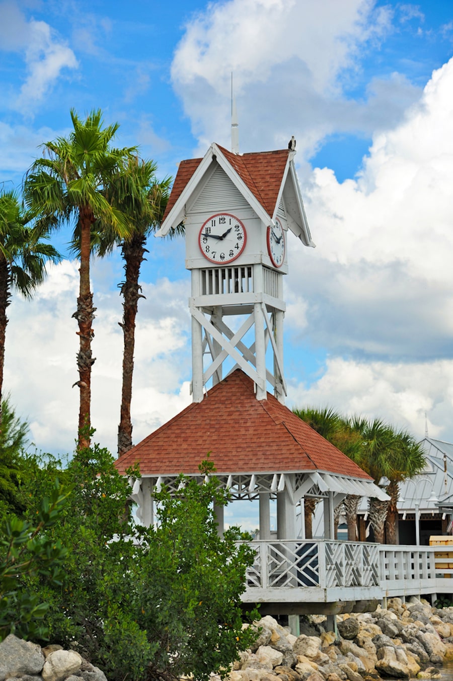 View of a historic beach pier with palm trees, a clock and blue skies, a great for spending some quality time together on your Anna Maria Island Romantic Getaway!