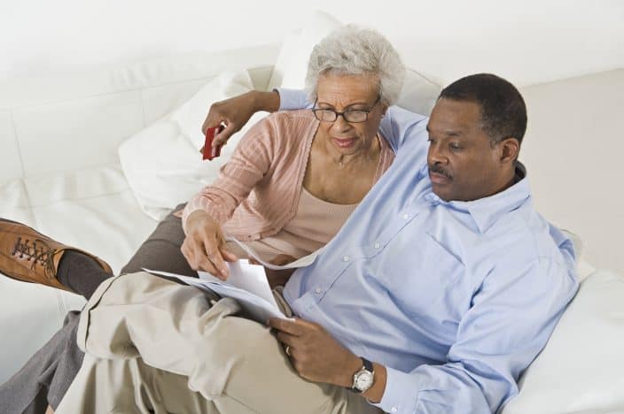 black man and black woman sitting down on sofa discussing finances