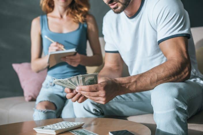 Couple counting money in the living room and budgeting