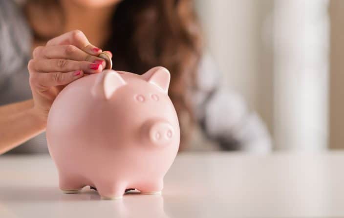 woman putting coins into a piggy bank for saving
