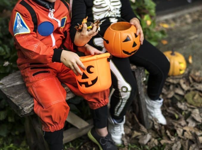 children in costumes sitting with candy after trick or treating as a free activity