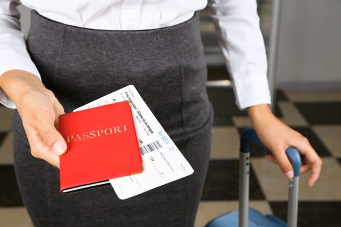 Woman with suitcase holding passport  and tickets making sure to have essential items handy