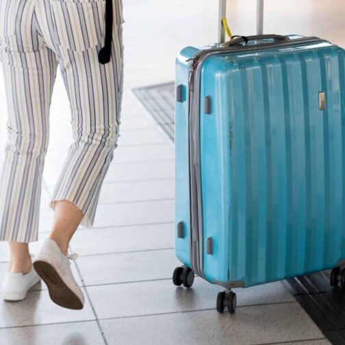 Blue suitcase with woman in striped pants
