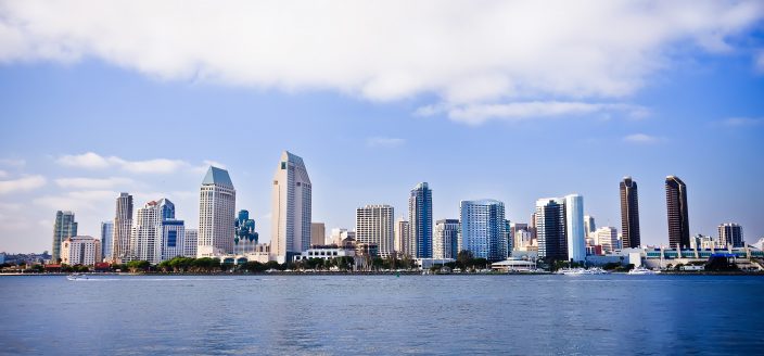 San Diego city skyline at sunset, showing the buildings of downtown rising above harbor viewed from Coronado Island. One of the best cities to retire in.
