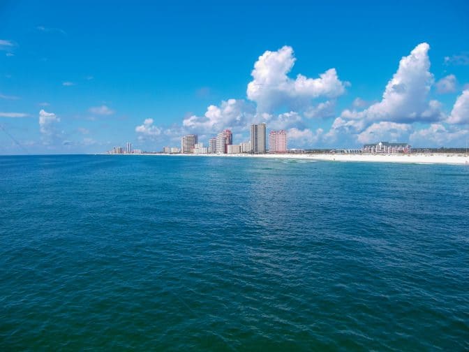 blue water view of orange beach, Alabama with hotels on the shore line