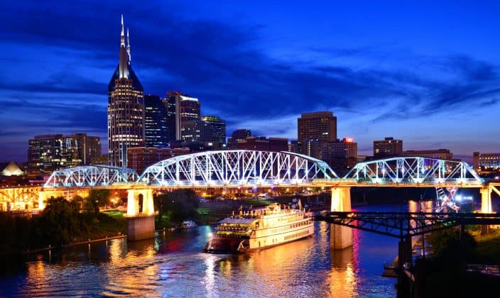 Night View of the Nashville bridge with city lights, skyscrapers, and cruise on the river. 