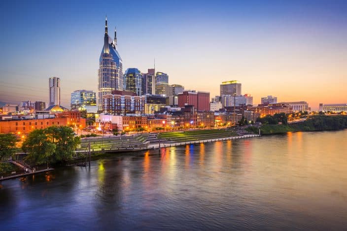 Cityscape view of the city of Nashville with skyscrapers and the Cumberland river with sunset skies. 
