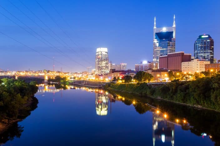 night view of the city of Nashville with river belt and reflection of lights from skyscrapers.