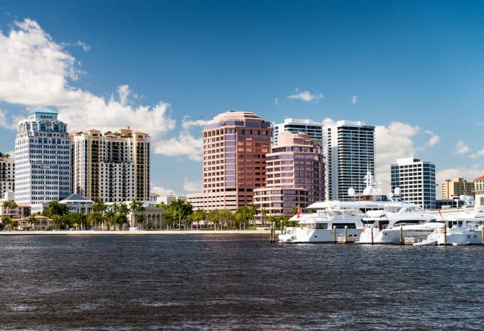 West Palm Beach, Florida. Panoramic city skyline, with skyscrapers, palm trees on the coastline, and yachts in the water, a great day trip from Fort Lauderdale