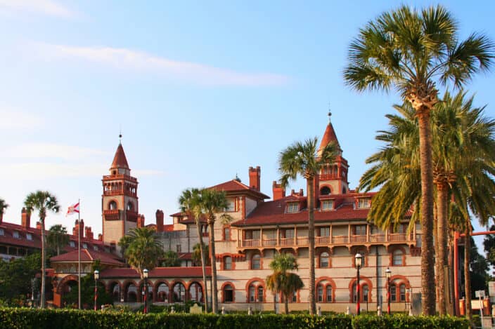 The Lightner Museum in St. Augustine, with blue skies, sunset light, and palm trees, an example of what to do while you are there