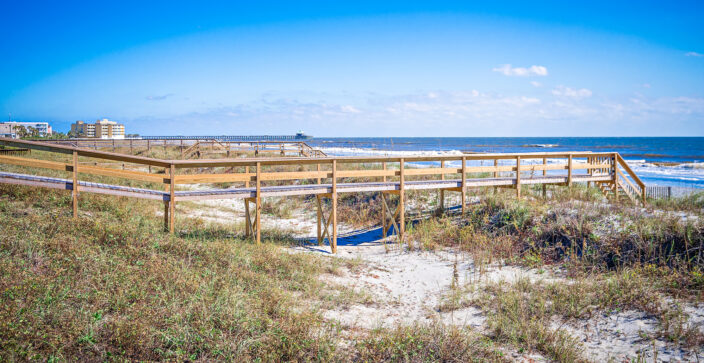 beach with grass and low dunes; wood walkway