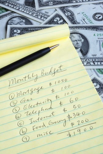 a list of of bills for the month on a lined notepad to make a budget for financial health