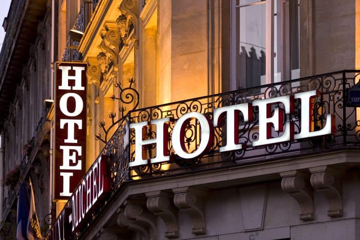 picture of a hotel window and balcony with a bright sign written “HOTEL” on it. 