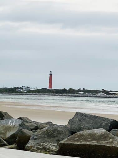 The Ponce Lighthouse in the distance on the beach with grey skies in New Smyrna Beach Florida