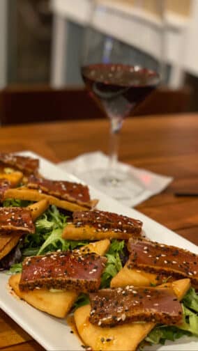 a tuna tataki appetizer with a glass of red wine at the restaurant Outriggers in new Smyrna Beach Florida