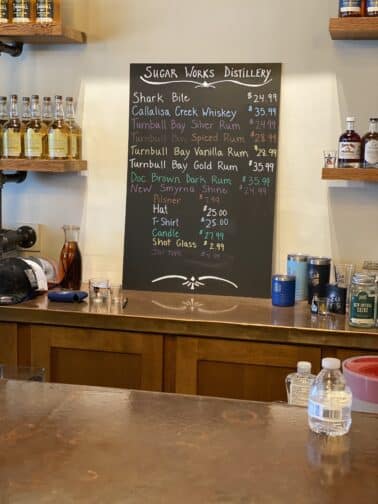 the view of the bar at Sugar Works Distillery with a chalk board sign that shows the special drinks of the day in New Smyrna Beach Florida