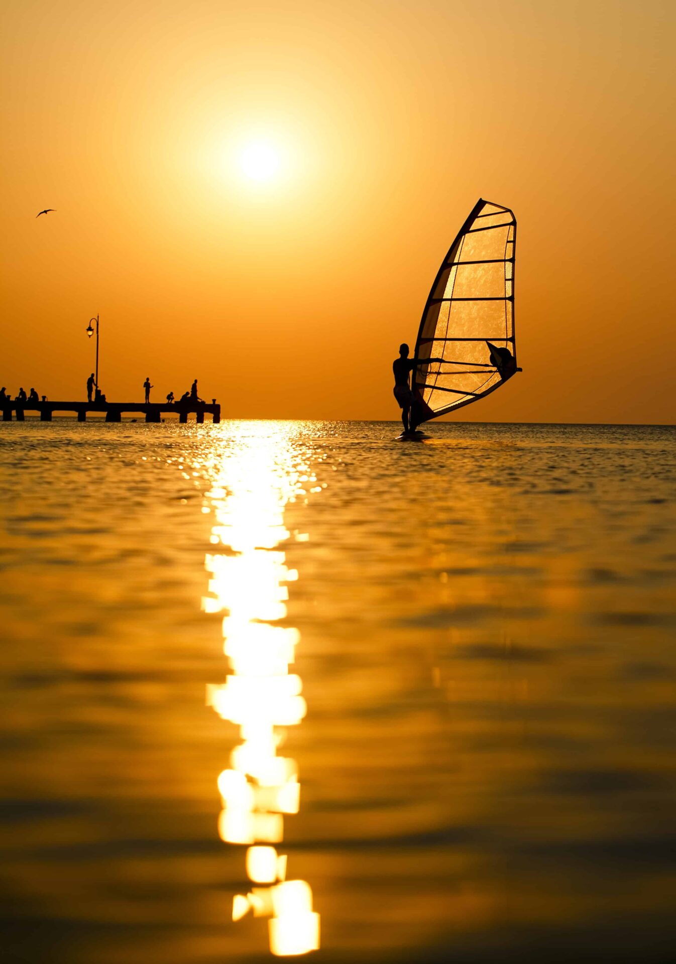 Discover Florida's Space Coast & Treasure Coast: Cocoa Beach: Man passing by with his windsurf or sailboard at sunset on a calm ocean against a spectacular vivid orange sky