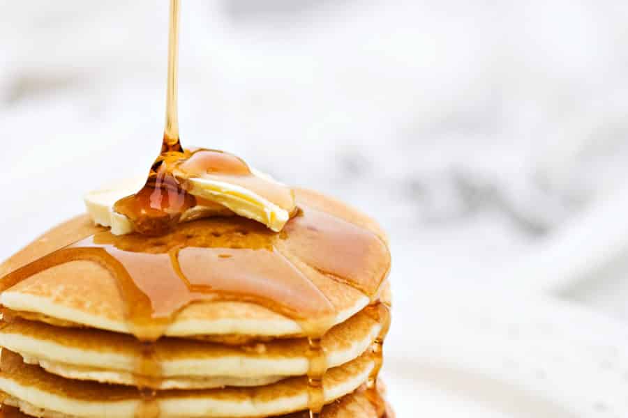 Stack of pancakes with butter and dripping with syrup