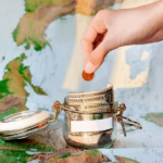 money jar with coins laying on world map