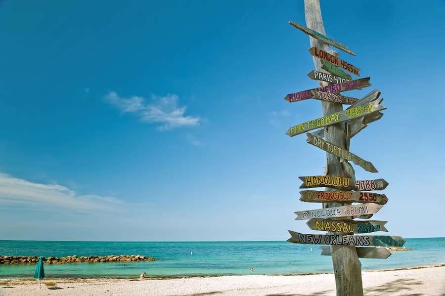 the beach and blue skies with a rustic wooden sign to represent the florida keys, a romantic weekend getaway destination