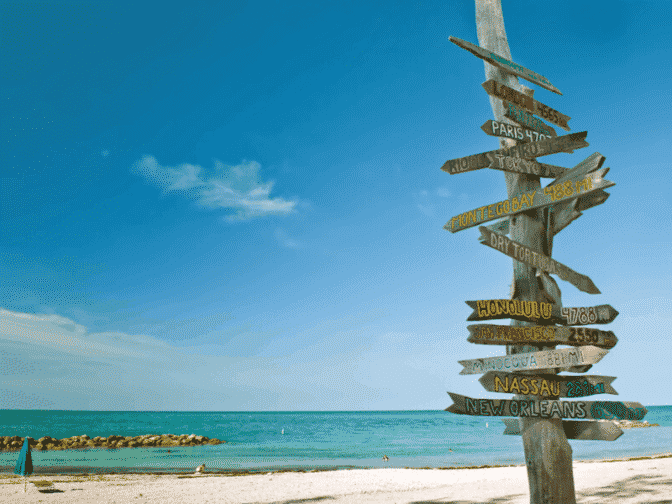 multi-colored mileage sign on beach