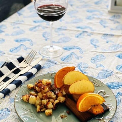 blue print table cloth with grilled citrus salmon and wine glass filled with red wine