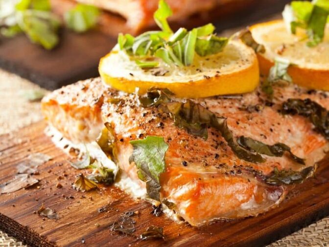 salmon on plank topped with lemon slices