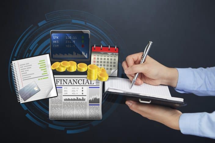 financial paper, budget, credit card, laptop, calendar and person wearing blue shirt holding a pen writing notes