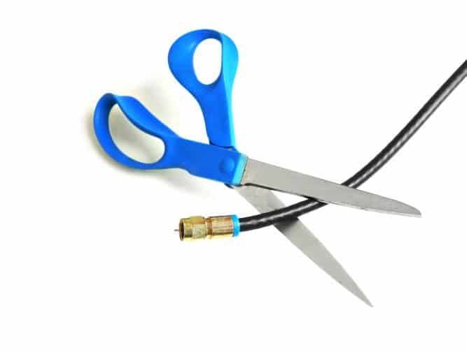 Scissors cutting through a coaxial cable - cut the cable tv concept; a good way to save money