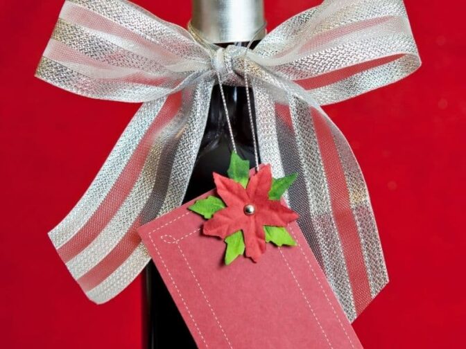 gift bottle of wine with red tag and red and white bow on red background is a great wine lovers holiday gift