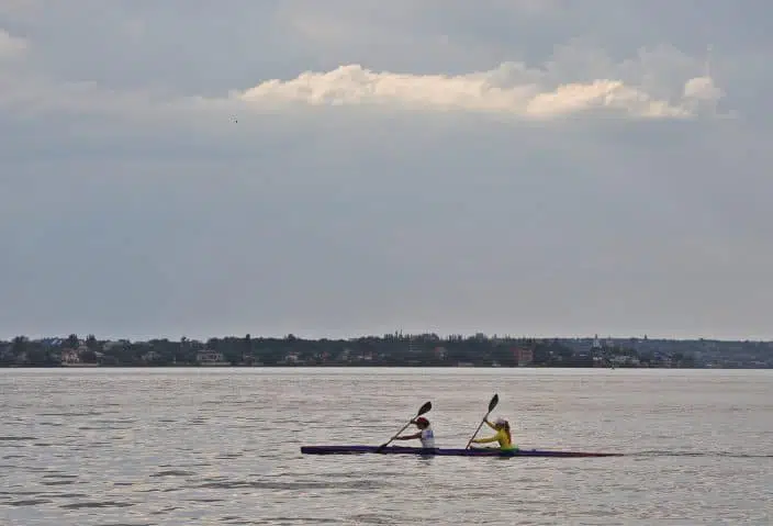 two people kayaking on the water with dark skies