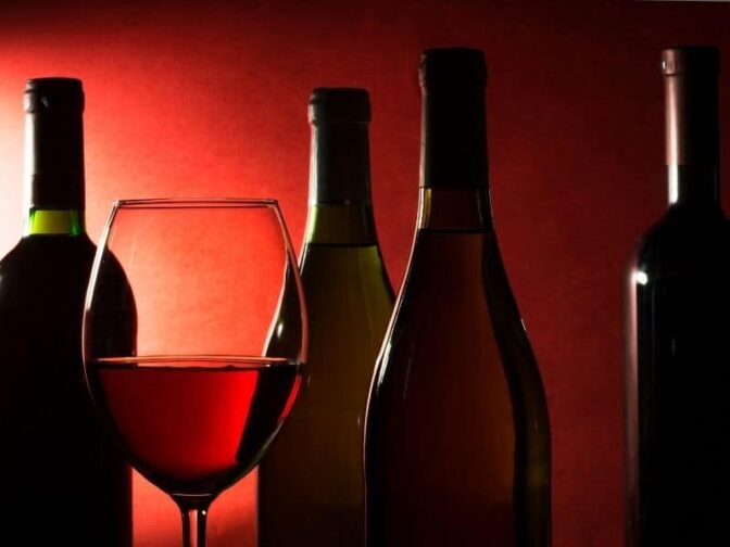 wine bottles and glass on red background