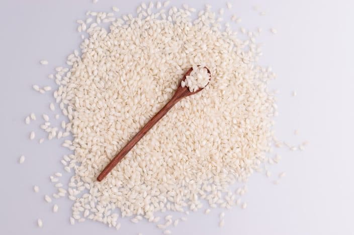 arborio rice on marble counter with a wooden spoon, used for making rice pudding