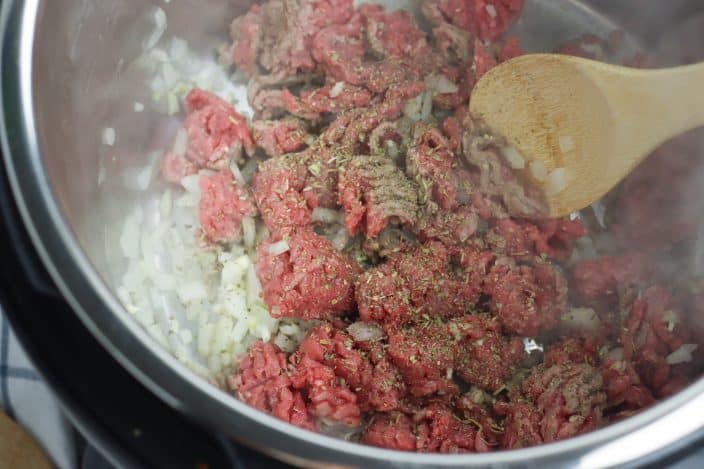 raw beef and onions in an instant pot to make spaghetti meat sauce