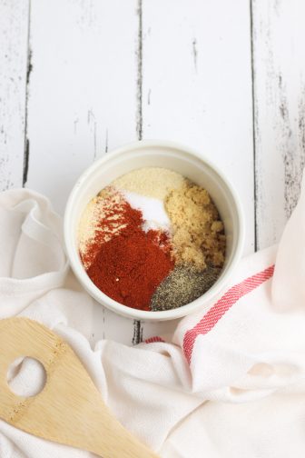 spices in a ramekin for a ribs dry rub on a white wooden background