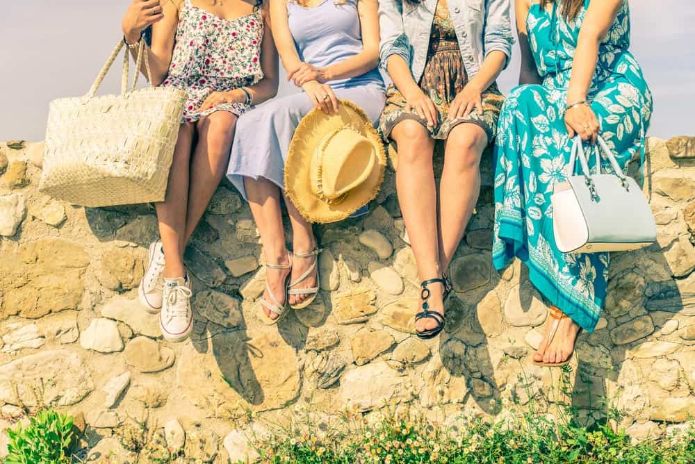 four girldfriends sitting on a stone wall on a getaway.