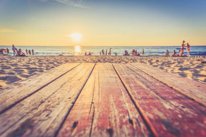 View of the beach with the sand, crowd, the sunset, and the sea all in one frame. 