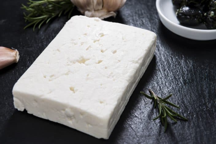 feta cheese on a cutting board for the making of greek salad skewers