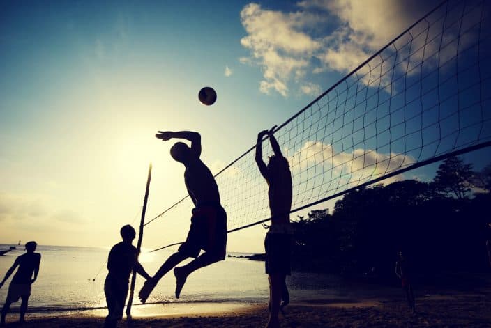 shadow of boys playing volleyball at the beach at sunset, a perfect beach day activity. 