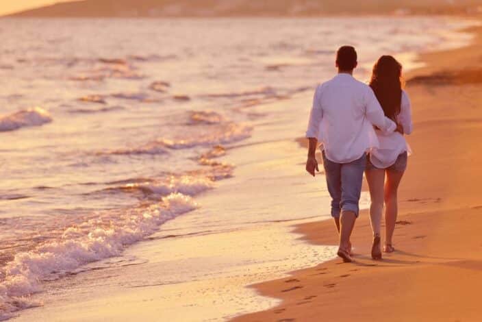 a man and woman walking on a beach