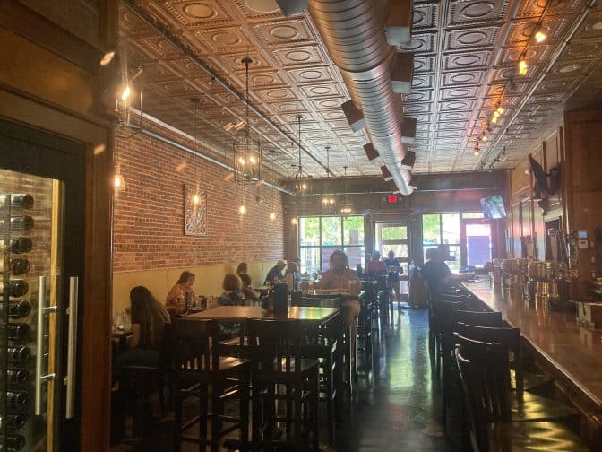 the interior at Clear Sky on Cleveland, with wood and copper interiors, bar tables and chairs and people enjoying food, an example of things to do in Clearwater Beach