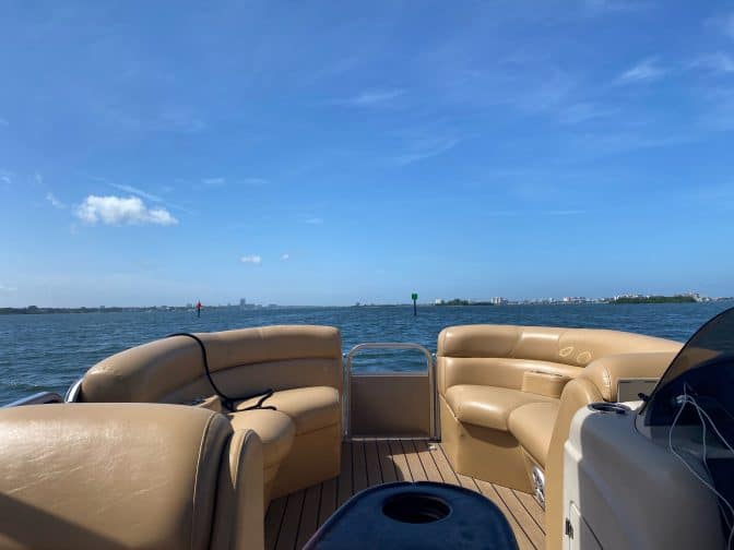 view from a pontoon boat with brown leather seating looking out over the blue bay with blue skies, an example of things to do in Clearwater beach