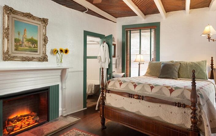 a bedroom suite at the St. Francis Inn with wood accents, a fireplace, fresh cut sunflowers, and teal accents