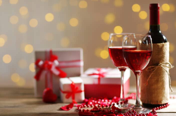 Setting of a bottle of wine, gifts in the boxes and other decoration, on blurred background with twinkly lights to represent wine gifts for wine lovers