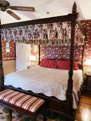 the king canopy bed in the Victoria Suite at Heron Cay bed and breakfast with red and white accents and floral wall paper