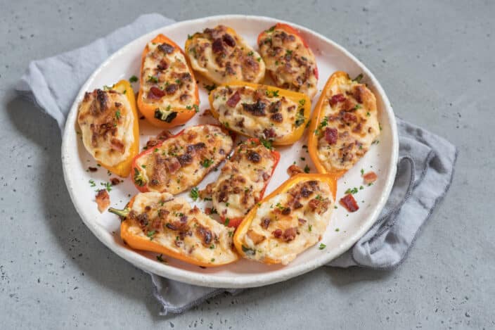 cheese stuffed mini peppers with bacon and herbs on a plate after broiling