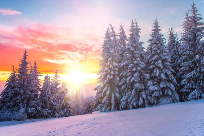 a winter landscape with sunset in the background 