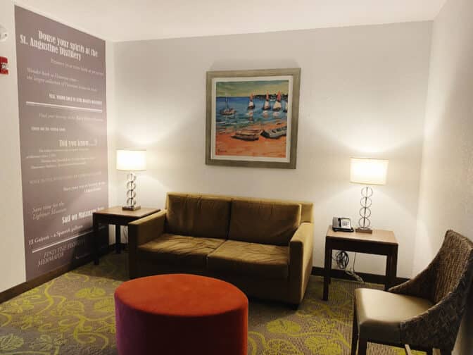 a seating room with a green couch, carpeted floors, lamps, and a painting on the wall at The Sebastian Hotel 
